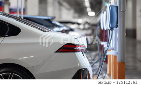 EV charging station and electric car, Electric car charging station for charge EV battery, Plug for vehicle with electric engine, EV charger clean energy, Charging point at car parking lot. 125112563