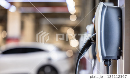 EV charging station and electric car, Electric car charging station for charge EV battery, Plug for vehicle with electric engine, EV charger clean energy, Charging point at car parking lot. EV charging station and electric car, Electric car charging station for charge EV battery, Plug for vehicle with electric engine, EV charger clean energy, Charging point at car parking lot. 125112567