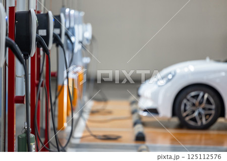 EV charging station and electric car, Electric car charging station for charge EV battery, Plug for vehicle with electric engine, EV charger clean energy, Charging point at car parking lot. EV charging station and electric car, Electric car charging station for charge EV battery, Plug for vehicle with electric engine, EV charger clean energy, Charging point at car parking lot. 125112576