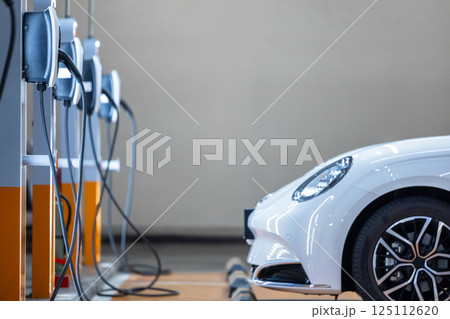 EV charging station and electric car, Electric car charging station for charge EV battery, Plug for vehicle with electric engine, EV charger clean energy, Charging point at car parking lot. EV charging station and electric car, Electric car charging station for charge EV battery, Plug for vehicle with electric engine, EV charger clean energy, Charging point at car parking lot. 125112620