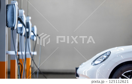 EV charging station and electric car, Electric car charging station for charge EV battery, Plug for vehicle with electric engine, EV charger clean energy, Charging point at car parking lot. 125112621