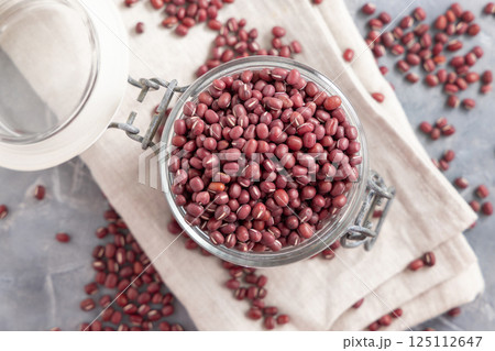 Glass jar full of azuki beans on gray top view. Dried uncooked legumes. Vegetarian protein 125112647