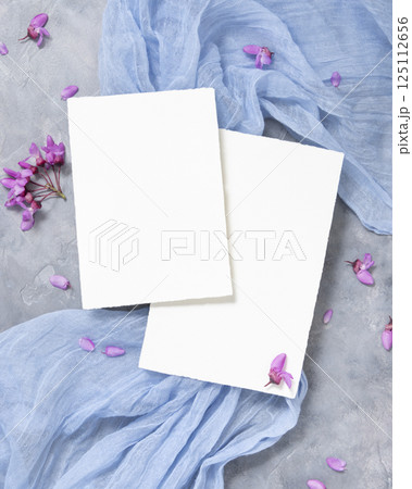 Vertical blank cards on fabric near wild purple flowers top view on gray, spring wedding mockup Vertical blank cards on fabric near wild purple flowers top view on gray, spring wedding mockup 125112656