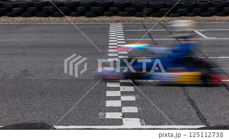 Motion blur kart driver crossing the start and finish line on kart race track circuit, Go kart racer crossing the start and finish line, Extreme sport competition winner. 125112738