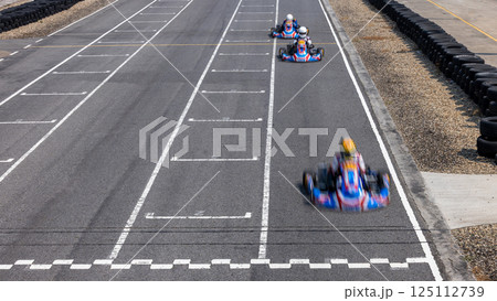 Motion blur kart driver crossing the start and finish line on kart race track circuit, Go kart racer crossing the start and finish line, Extreme sport competition winner. 125112739