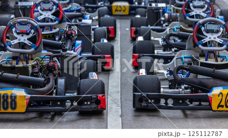 Race go kart car in row on the pit lane, Racing kart wait for race, Go kart car park on race track, Row of go kart car ready to race. Race go kart car in row on the pit lane, Racing kart wait for race, Go kart car park on race track, Row of go kart car ready to race. 125112787