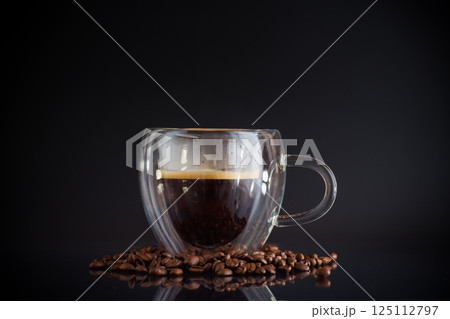 A cup of hot coffee with coffee beans on a black background A cup of hot coffee with coffee beans on a black background 125112797