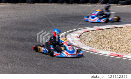Motion blur kart driver drive go kart on kart race track circuit, Go kart racer driver on curve race track, Extreme sport Motion blur kart driver drive go kart on kart race track circuit, Go kart racer driver on curve race track, Extreme sport 125112831
