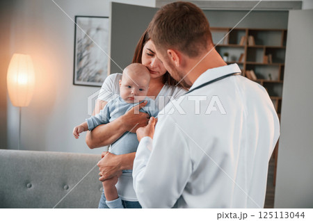 Woman holding her newborn baby in hands. Male doctor is indoors Woman holding her newborn baby in hands. Male doctor is indoors 125113044