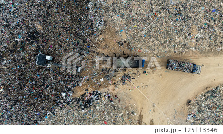 Garbage dump pile in trash dump or landfill, Landfill with waste disposal, Garbage truck unloads rubbish in landfill, Truck waste dump waste from household, Excavator work garbage waste, Aerial view. 125113346