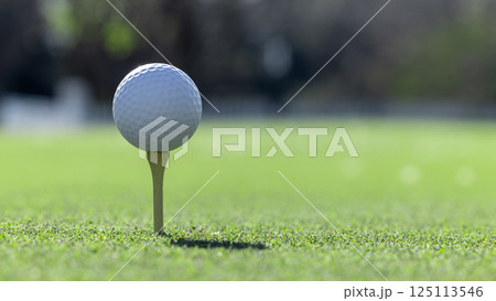 White golf ball on wooden tee on green grass background, Golf ball on tee ready to be shot, Golf ball close up on green grass. 125113546