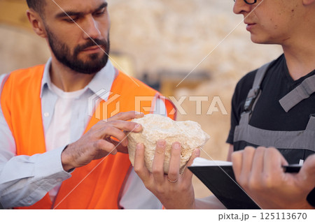Checking rock that is in the hands. Two men in uniform are working together in the quarry 125113670