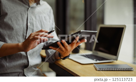 Young entrepreneur working with digital tablet and laptop at desk 125113723