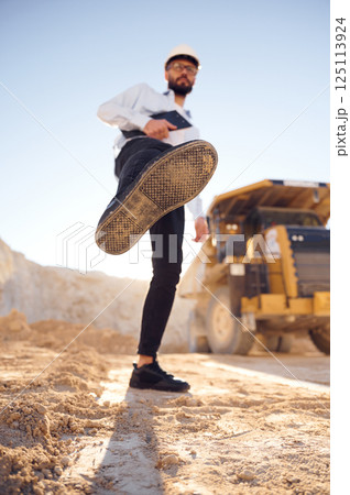 Having fun, making a kick by leg. Man in uniform is working in the quarry at daytime Having fun, making a kick by leg. Man in uniform is working in the quarry at daytime 125113924