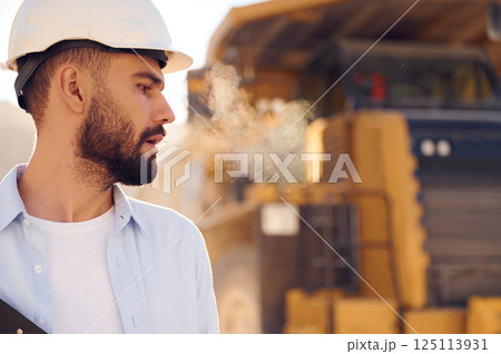 Beautiful man in uniform is working in the quarry at daytime. With haul truck 125113931
