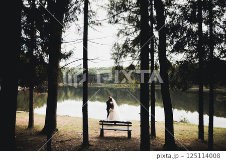 Newly married couple running and jumping in park while holding hands 125114008