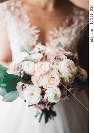 Bride holding big and beautiful wedding bouquet with flowers Bride holding big and beautiful wedding bouquet with flowers 125114056