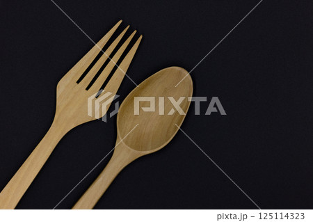 Wooden spoon and fork on black background, One set of wood spoon and fork kitchen ware, Eco friendly Wooden fork and spoon, Top view Wooden spoon and fork on black background, One set of wood spoon and fork kitchen ware, Eco friendly Wooden fork and spoon, Top view 125114323