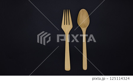 Wooden spoon and fork on black background, One set of wood spoon and fork kitchen ware, Eco friendly Wooden fork and spoon, Top view Wooden spoon and fork on black background, One set of wood spoon and fork kitchen ware, Eco friendly Wooden fork and spoon, Top view 125114324