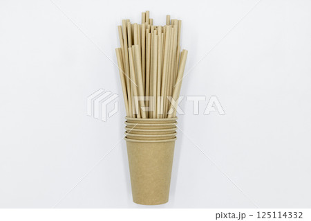 Paper cups and paper straws on white background, Accessories for drinking outdoors, Ecology recycling eco friendly, Eco friendly reusable paper straws, Kraft paper straw for drinking coffee or tea. 125114332
