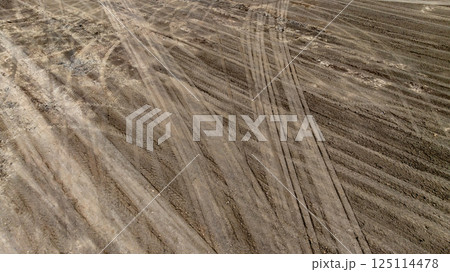 Tyre track on dirt sand or mud off road track, Tire mark ground vehicle wheel shape, Dirt soil texture, Top view tires tracks on dry mud background and texture. Tyre track on dirt sand or mud off road track, Tire mark ground vehicle wheel shape, Dirt soil texture, Top view tires tracks on dry mud background and texture. 125114478