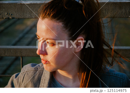 Pensive woman on bridge at sunset for reflective mood themes 125114975