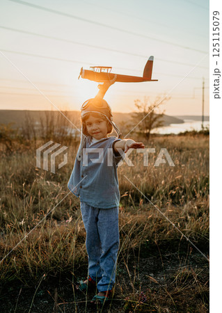 Portrait funny little boy in aviator helmet ready to fly as airplane on nature Portrait funny little boy in aviator helmet ready to fly as airplane on nature 125115079