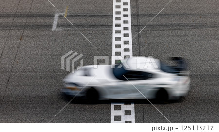 Motion blurred super car crossing finish line checkered on race track circuit, Race super car blurred motion crossing finish checkered line on race track, concept win and goal reached. 125115217