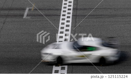 Motion blurred super car crossing finish line checkered on race track circuit, Race super car blurred motion crossing finish checkered line on race track, concept win and goal reached. Motion blurred super car crossing finish line checkered on race track circuit, Race super car blurred motion crossing finish checkered line on race track, concept win and goal reached. 125115224