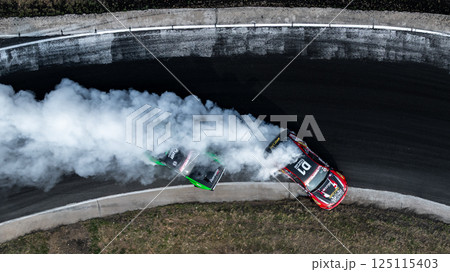 Top view two race car drift battle on race track with white smoke, Drift battle race car competition drift, Car drift battle on race track, Motorsport race car. 125115403