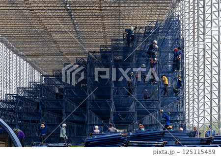 All workers to build scaffold for working at height of building under construction, Group man worker  working on assembly of scaffold, Worker installing scaffolding on building showcasing teamwork 125115489