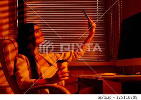 Confident Woman Taking Selfie in Office Chair with Coffee. 125116289