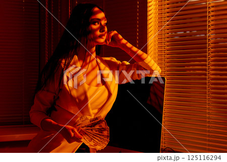 Stylish Businesswoman Holding Cash Fan in Sunset Light. Stylish Businesswoman Holding Cash Fan in Sunset Light. 125116294