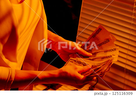 Female Hands Holding Euro and Dollar Banknotes in Warm Office Light. Female Hands Holding Euro and Dollar Banknotes in Warm Office Light. 125116309