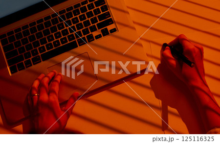 Female Hands Drawing on Paper beside Laptop with Dramatic Light. 125116325