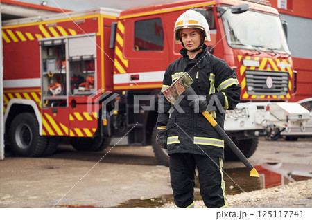 In uniform with axe in hands. Woman firefighter is at work in department In uniform with axe in hands. Woman firefighter is at work in department 125117741