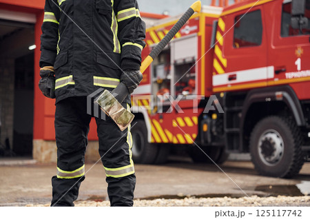 In uniform with axe in hands. Woman firefighter is at work in department In uniform with axe in hands. Woman firefighter is at work in department 125117742