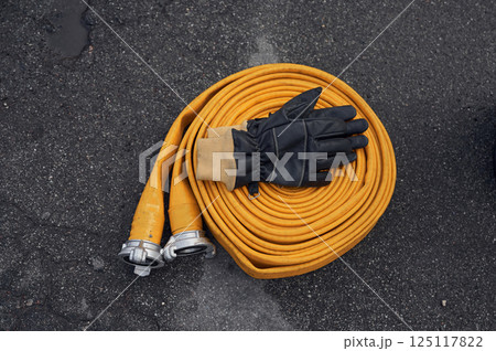 Top view of yellow fire hose with black gloves on it on the ground Top view of yellow fire hose with black gloves on it on the ground 125117822