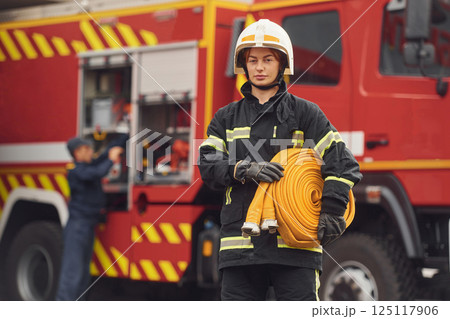 Holding fire hose. Woman in uniform is at work in department 125117906