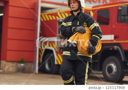 Holding fire hose. Woman in uniform is at work in department 125117908