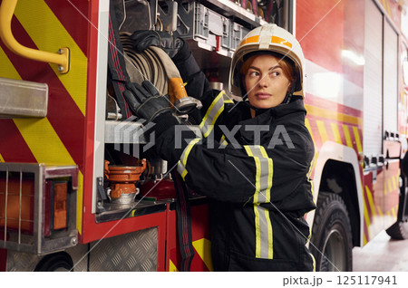 Taking equipment from the truck. Woman firefighter in uniform is at work in department 125117941
