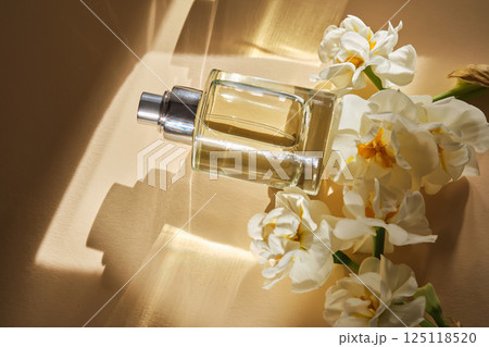 Perfume on a beige background in the rays of bright sun with beautiful highlights. Perfume on a beige background in the rays of bright sun with beautiful highlights. 125118520