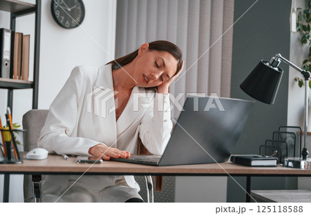 Feeling tired, having headache. Young beautiful woman in formal clothes is working at office 125118588