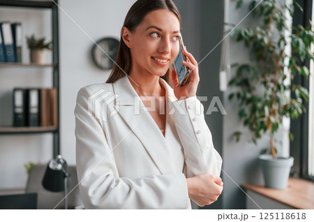 Talking by phone. Young beautiful woman in formal clothes is working at office 125118618