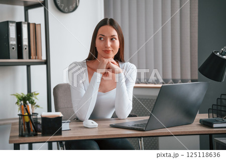 Smiling for the camera. Young beautiful woman in white clothes is in the office 125118636