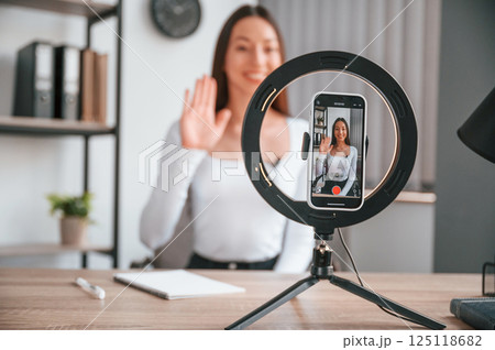 Talking, doing online master class. Young beautiful woman in white clothes is in the office Talking, doing online master class. Young beautiful woman in white clothes is in the office 125118682