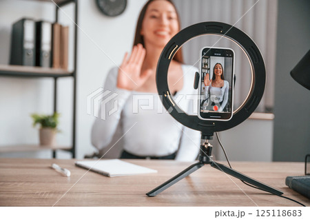 Talking, doing online master class. Young beautiful woman in white clothes is in the office Talking, doing online master class. Young beautiful woman in white clothes is in the office 125118683