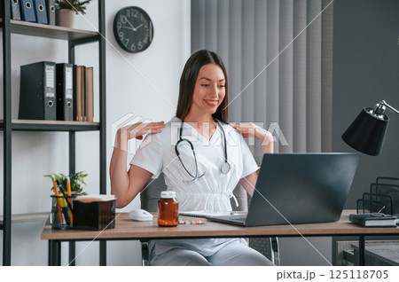 Doing online consultation. Young beautiful female doctor in white coat is in the office Doing online consultation. Young beautiful female doctor in white coat is in the office 125118705