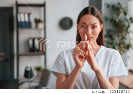 Conception of vaccination. With syringe in hands. Young beautiful female doctor in white coat is in the office Conception of vaccination. With syringe in hands. Young beautiful female doctor in white coat is in the office 125118736