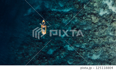 Kayaking in blue sea on transparent kayak. Drone view with copy space Kayaking in blue sea on transparent kayak. Drone view with copy space 125118804